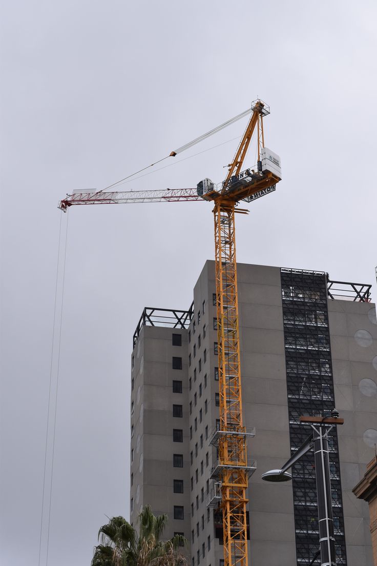 Tower crane working beside an active high-rise building under construction.
