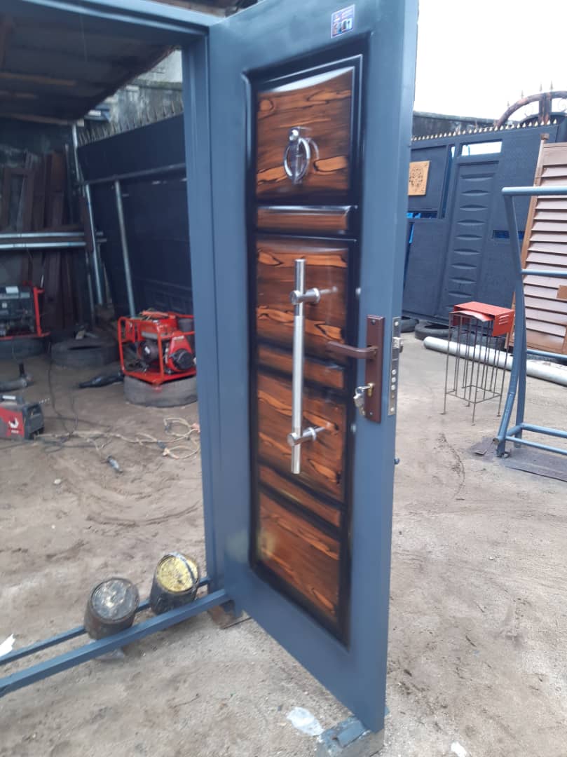 Fabricated security door with a wood-finish panel and reinforced frame.
