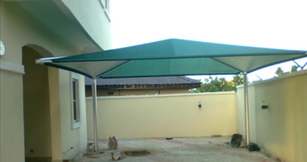 Green tension canopy installed over a paved courtyard for shade and comfort.