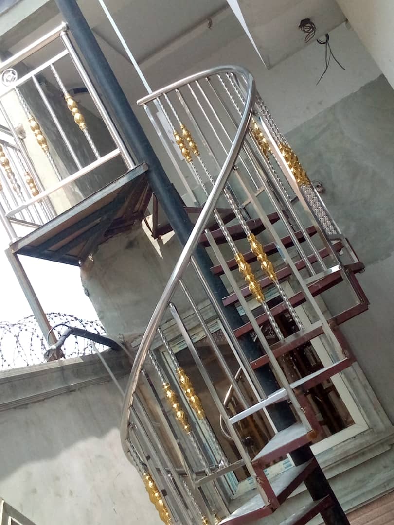Indoor spiral staircase with polished stainless balustrade and gold accents.